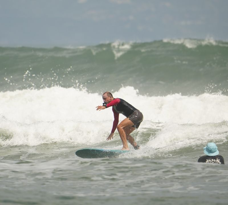 Bobby Bastviken surfer en bølge på et turkis longboard, med skum bak seg